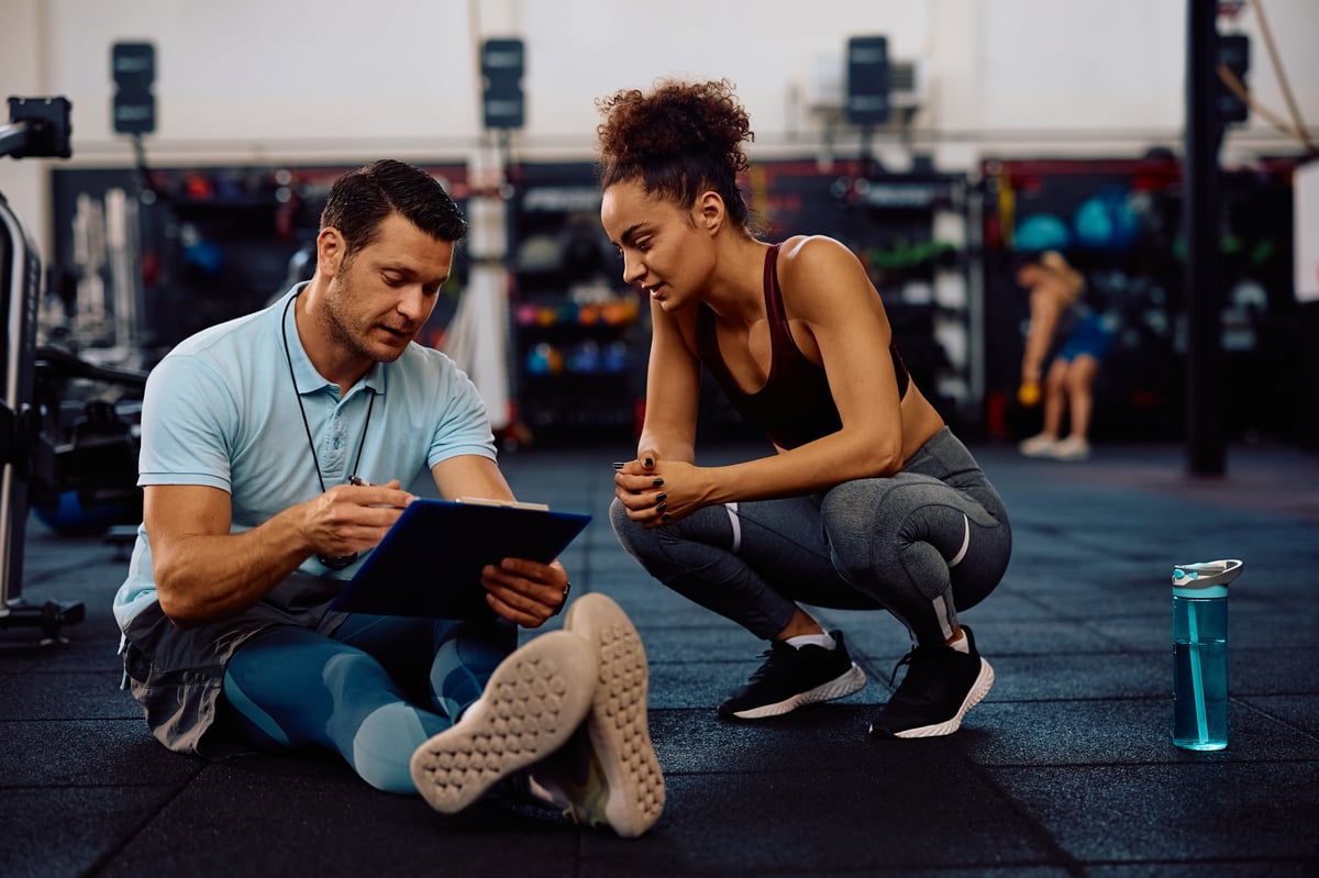 Professional personal trainer analyzing client exercise plan
